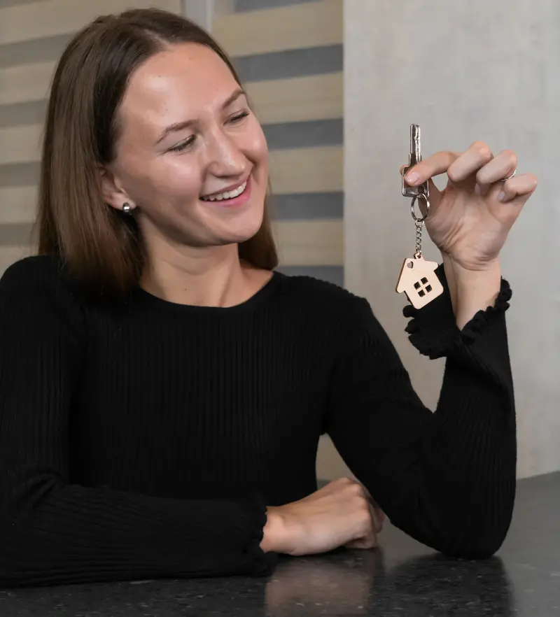 Smiling woman holding house keychain and key.